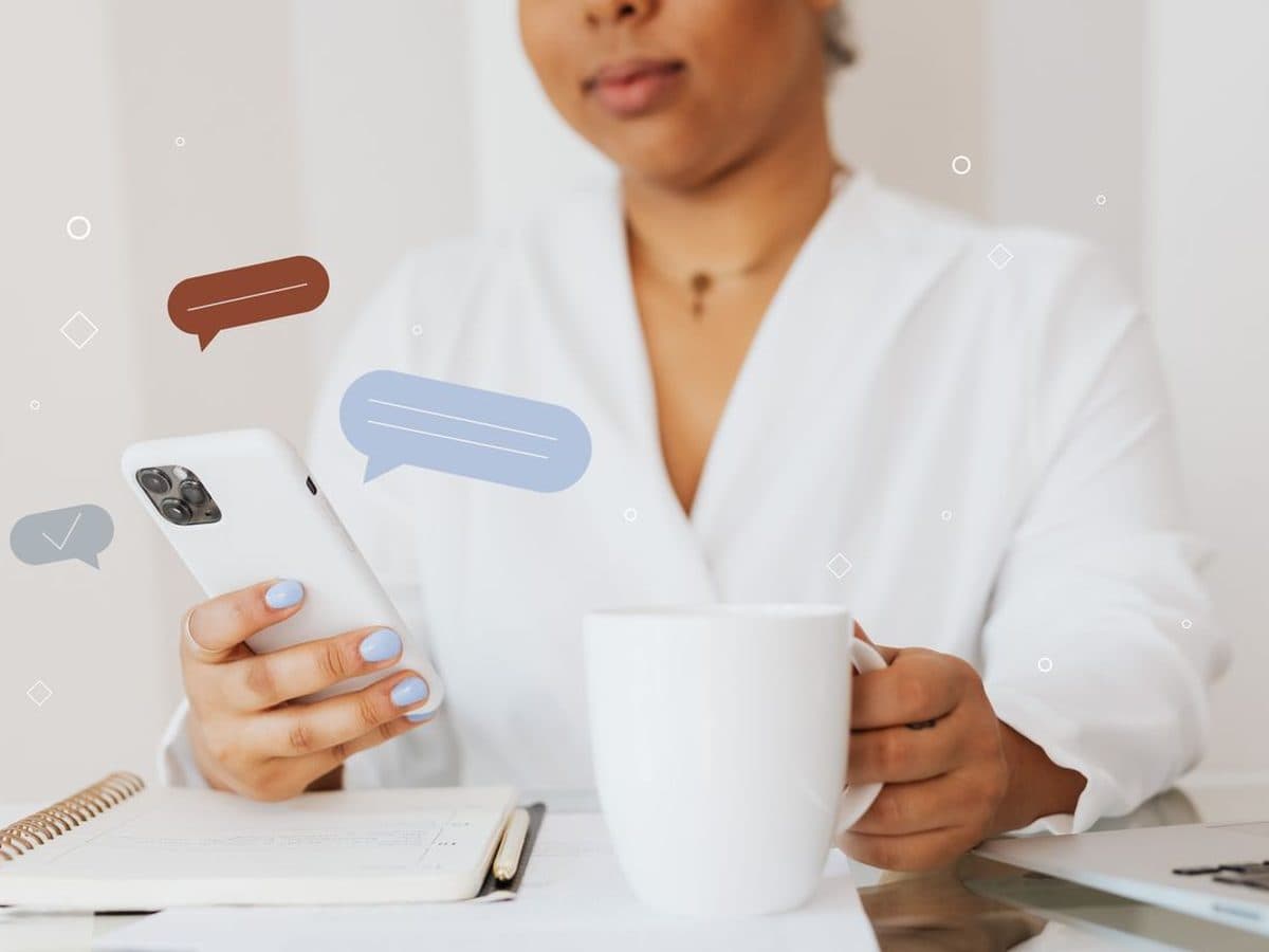 Pessoa conversa pelo celular com balões de mensagem ao redor