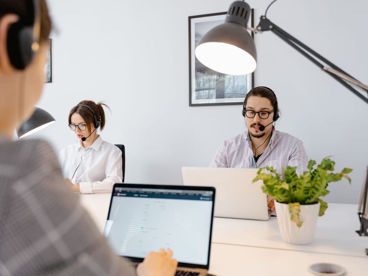 Atendente com headset trabalhando no notebook em escritório claro