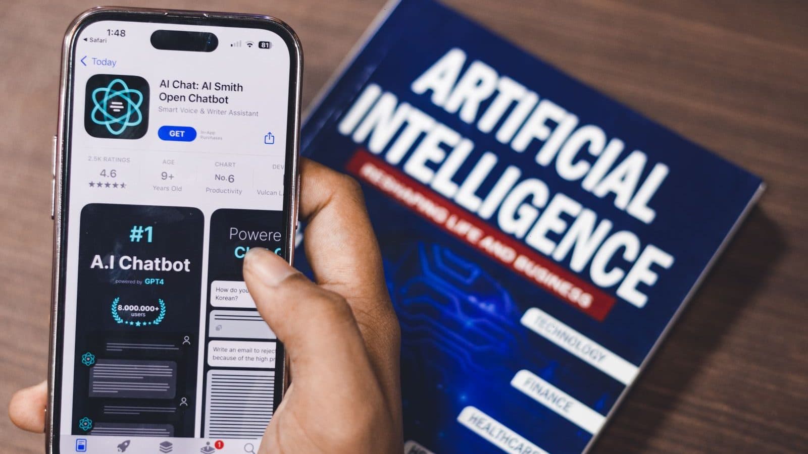 Celular exibindo aplicativo de assistente de IA ao lado de um livro sobre inteligência artificial